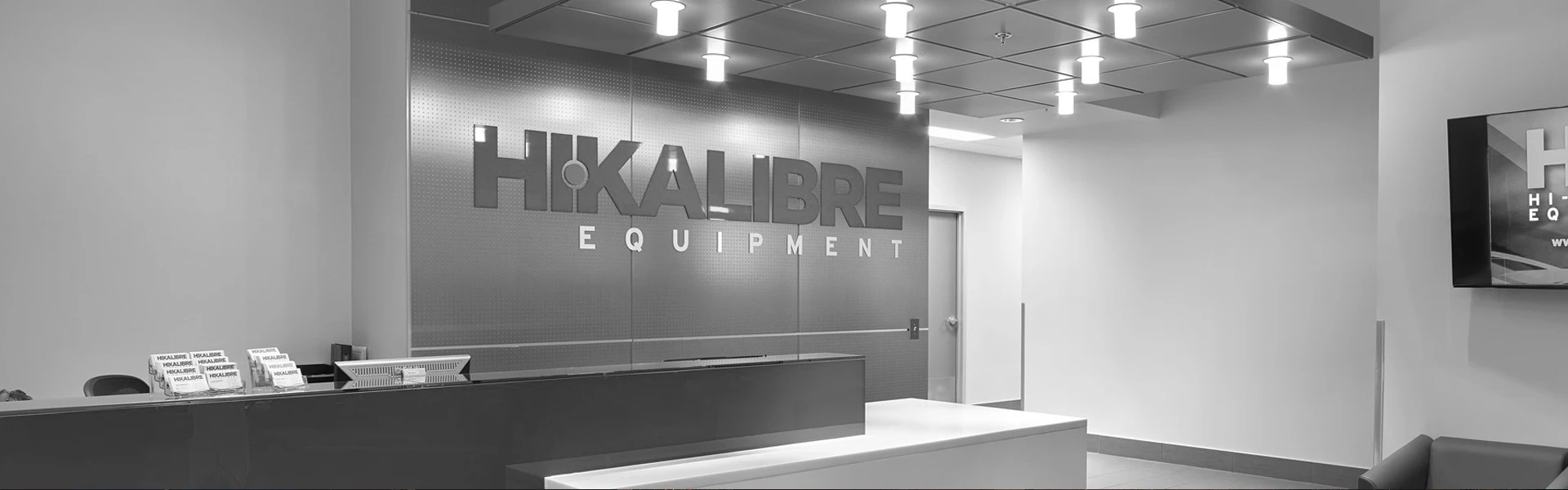 Black and white photo of Hi-Kalibre front desk with logo sign