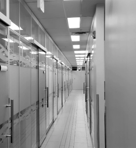 Hallway with glass doors on the left and cubicles on the right side in black and white