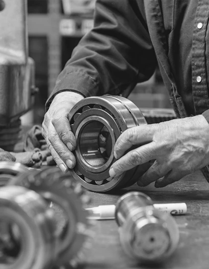 A man's hands holding wheel shaped equipment in black and white